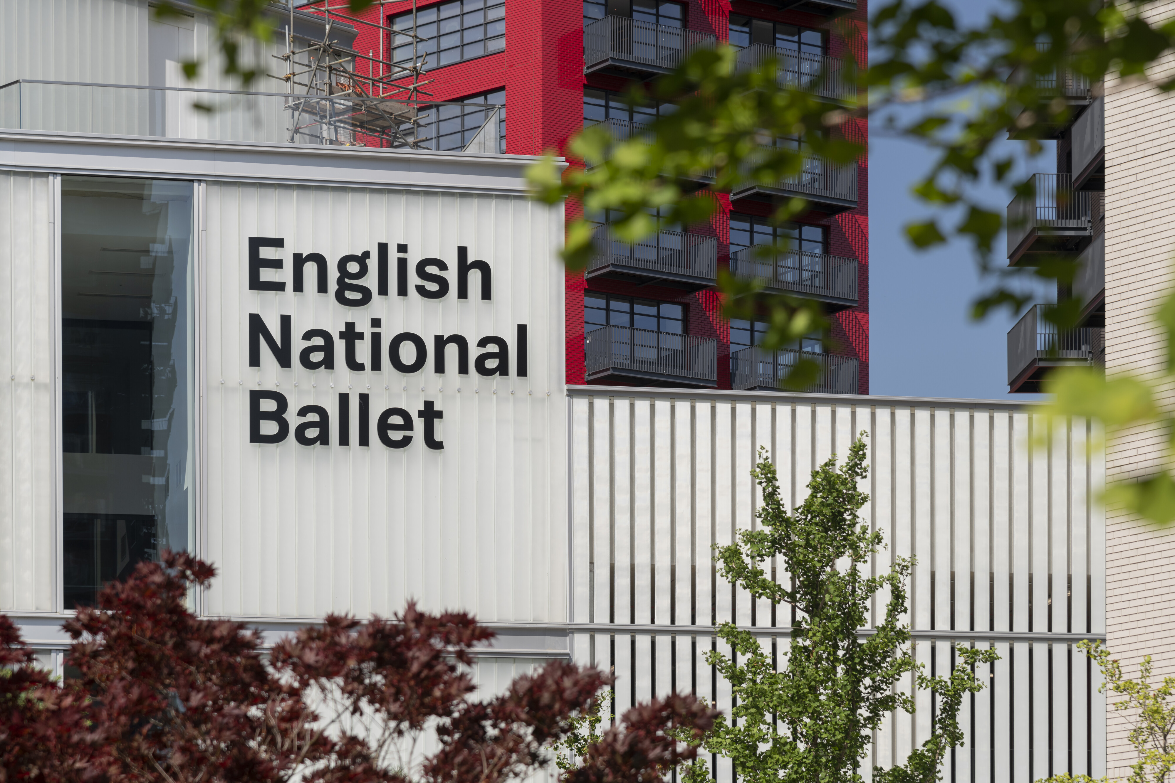 Building facade reading “English National Ballet,” with balconies, scaffolding, and trees.