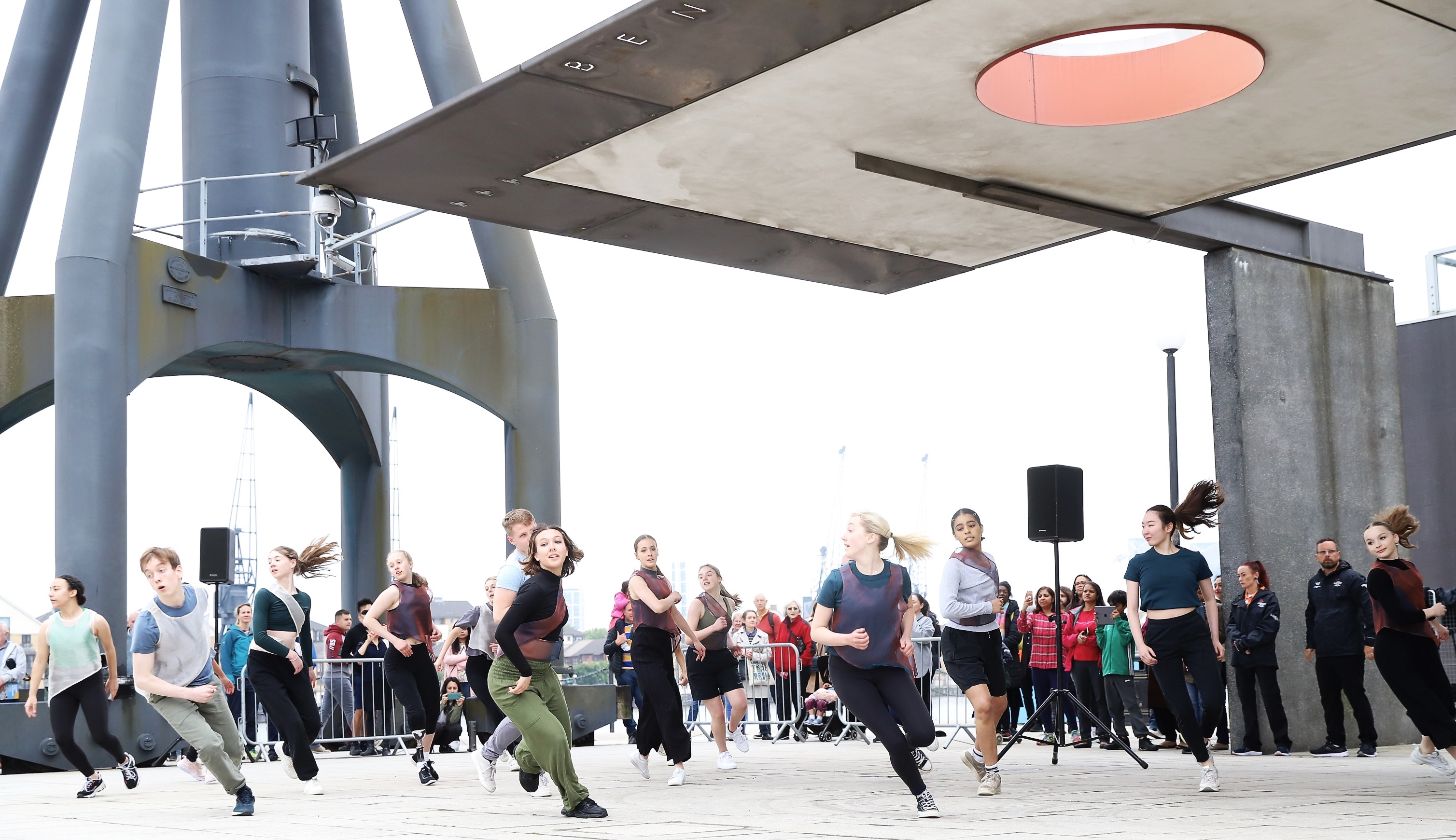Group of dancers in public outside space dancing.